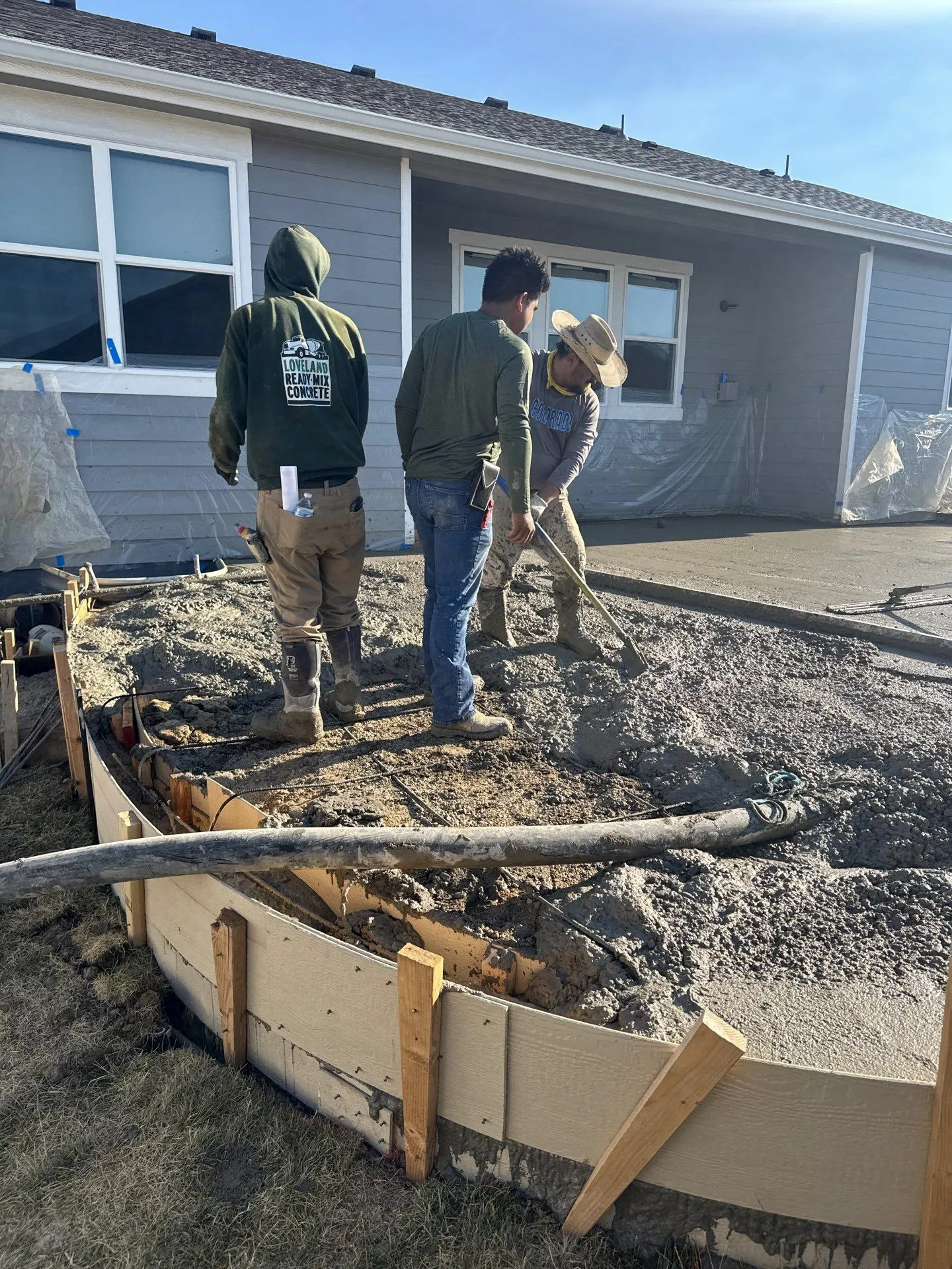 Fort August Construction crew pouring and shaping concrete for a curved residential patio installation