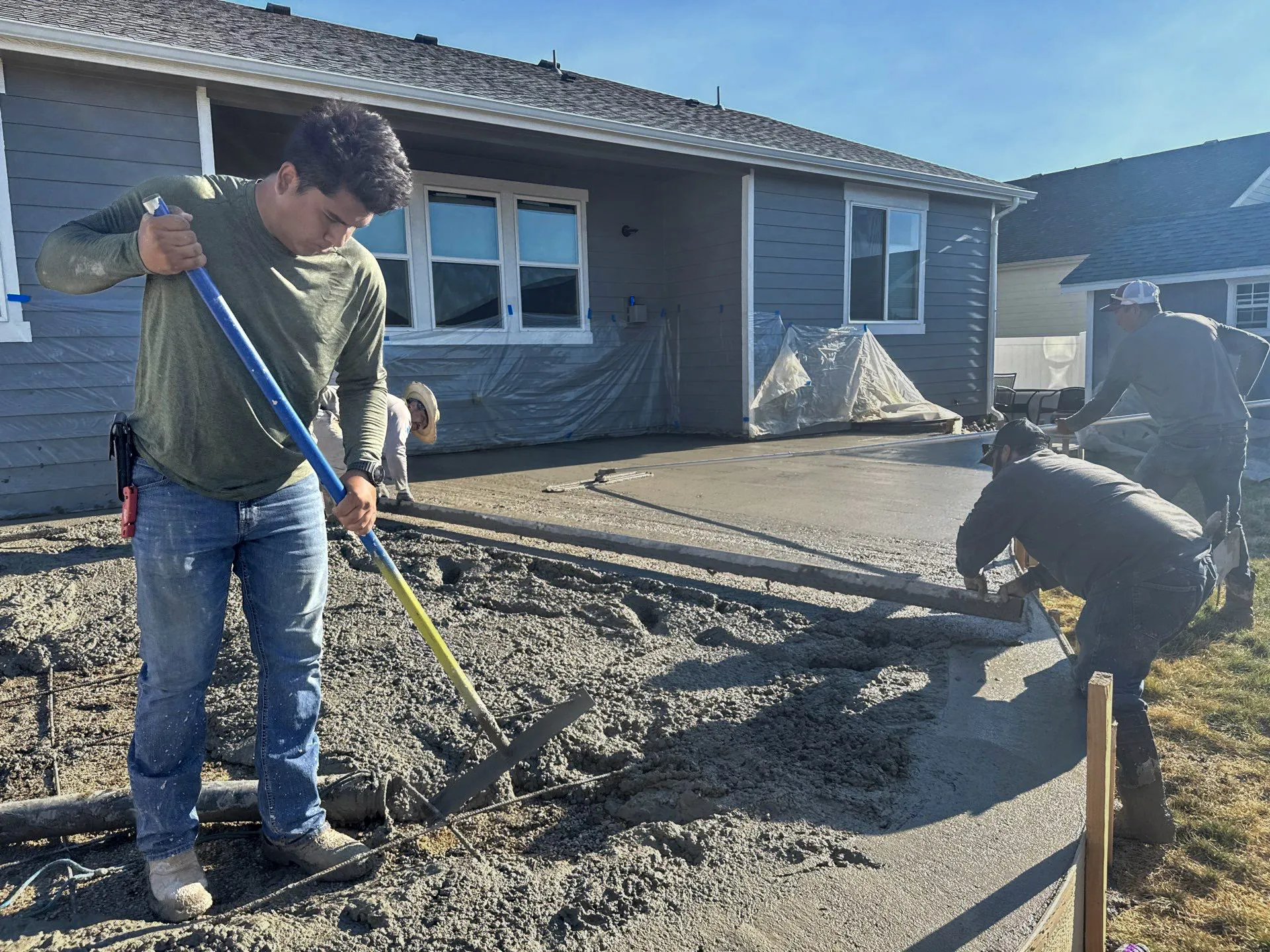 Fort August Construction crew pouring and leveling fresh concrete for a residential patio installation