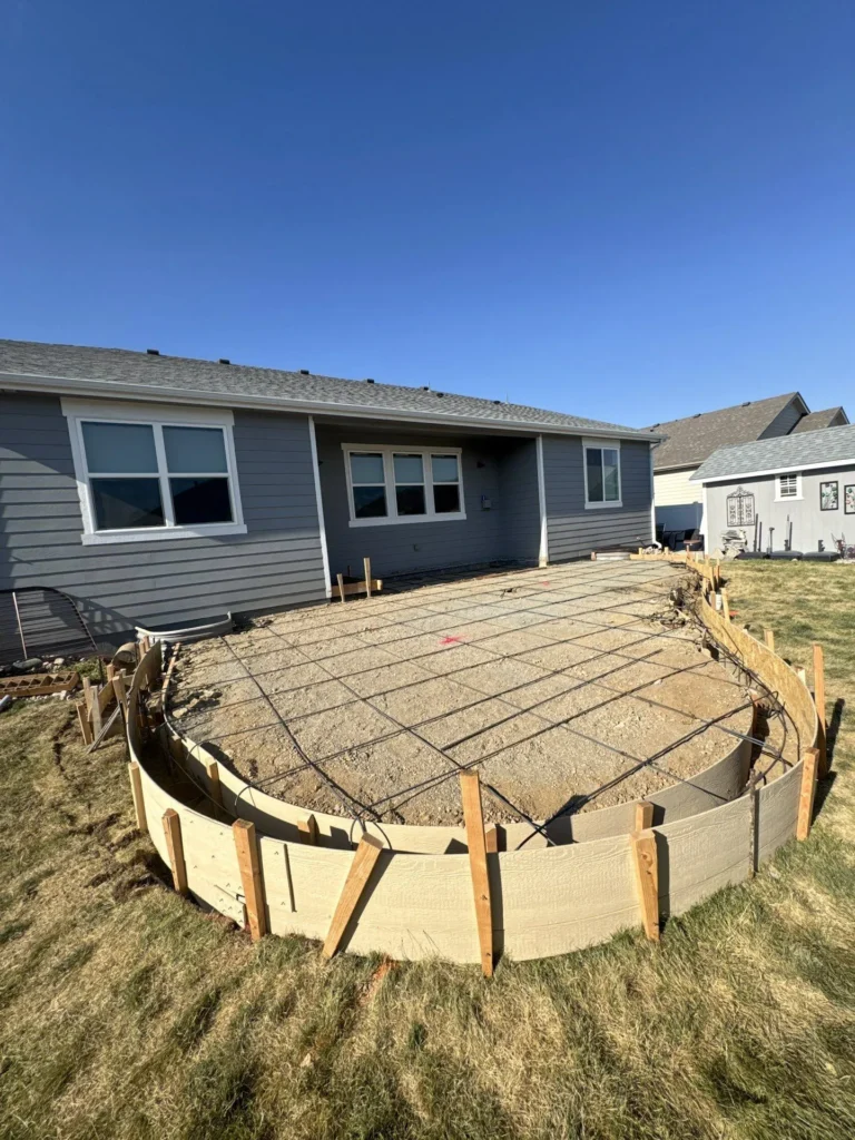 Fort August Construction preparing curved patio with wooden forms and rebar grid before concrete pour