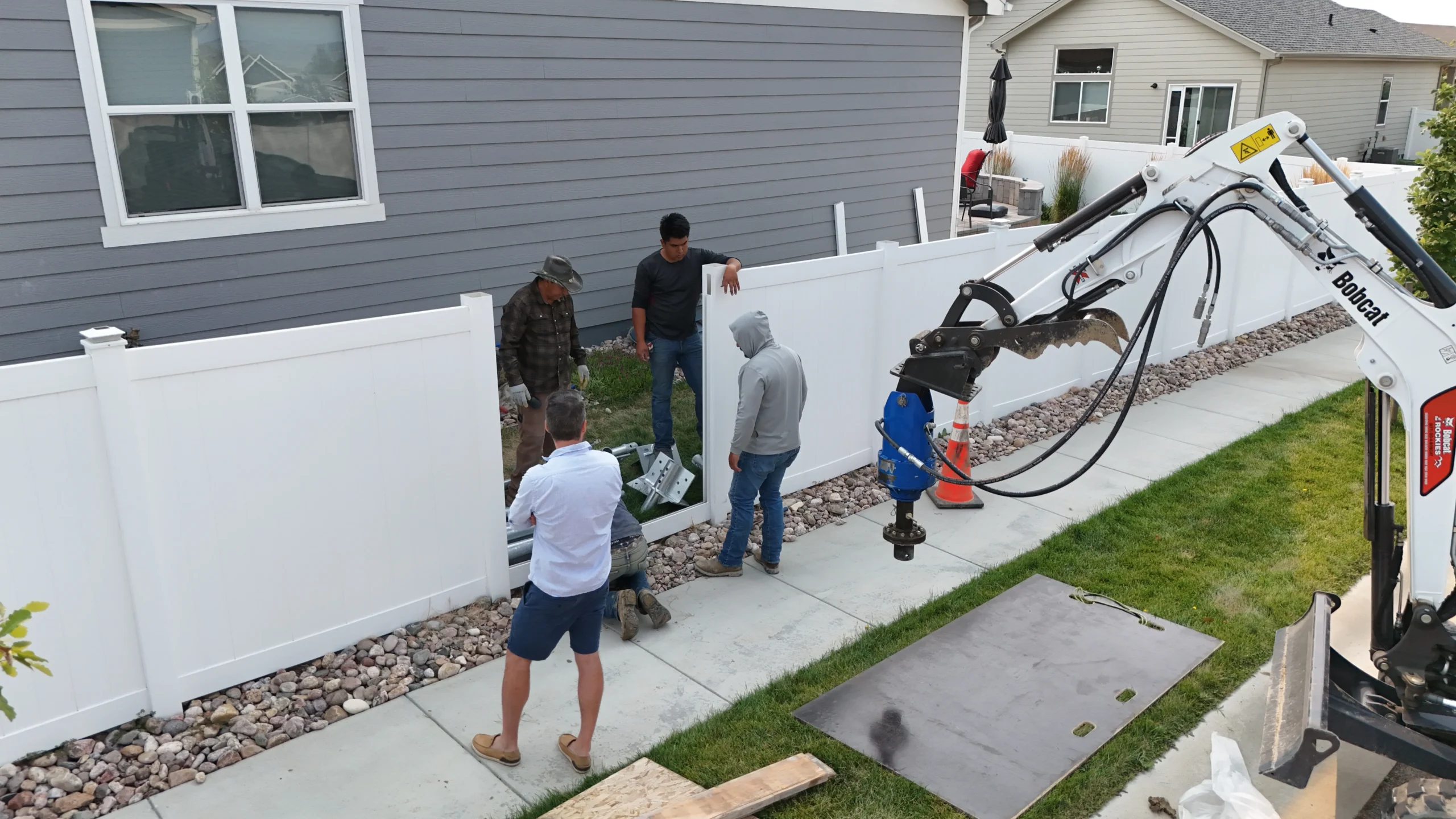 Fort August Construction crew preparing helical pier equipment in side yard for residential foundation repair