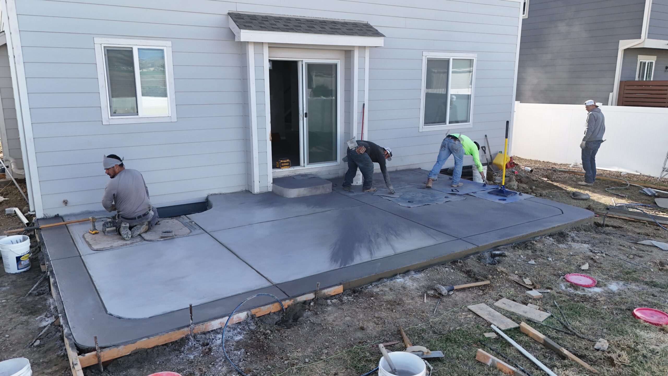 Fort August Construction crew installing a stamped concrete patio with color hardener application in Longmont, Colorado