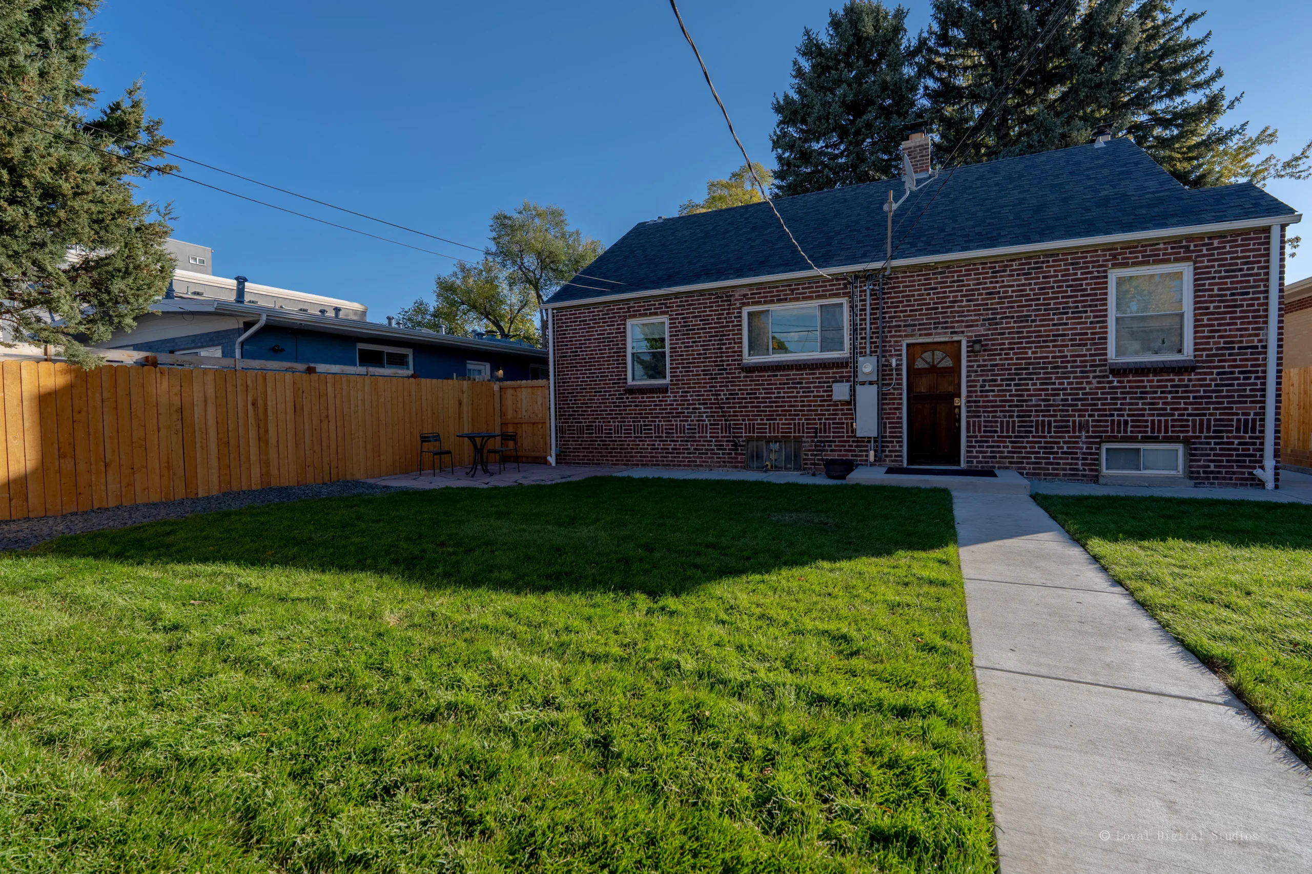 Wide view of backyard concrete walkway and fresh sod installation by Fort August Construction in Denver, Colorado.